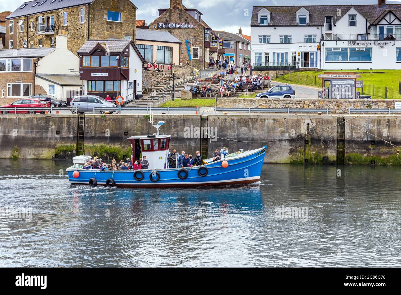 Ein Touristenboot kehrt von den nahe gelegenen Farne Islands nach Seahouses Harbour in Northumberland zurück, wo auch eine kleine Fischereiflotte beheimatet ist. Stockfoto