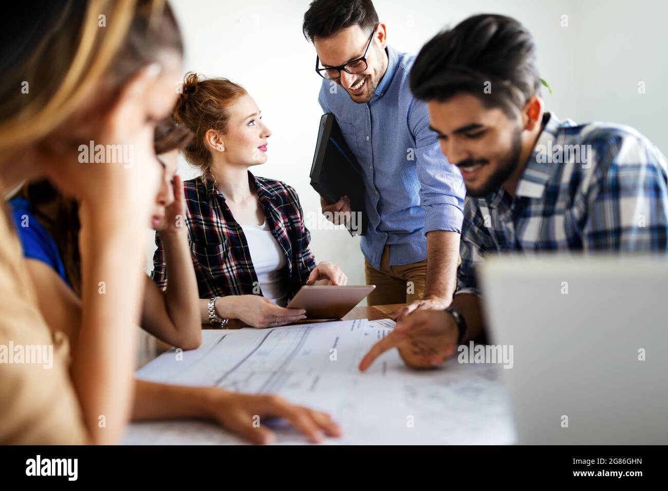 Glückliche, multiethnische Gruppe von Geschäftsleuten, die gemeinsam an einem Treffen im Büro arbeiten Stockfoto