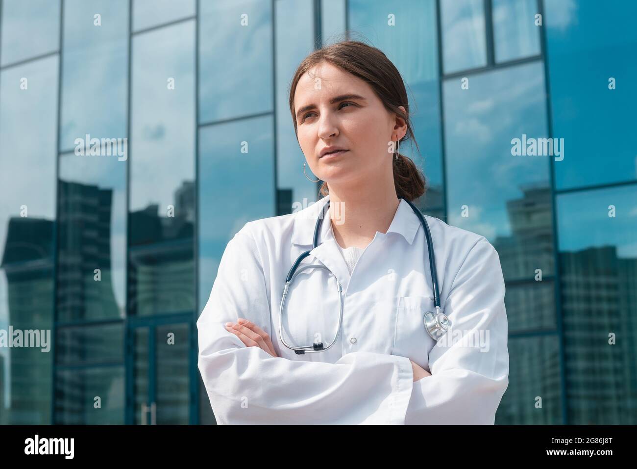 Junge Ärztin, die vor dem Krankenhaus steht. Nahaufnahme. Stockfoto