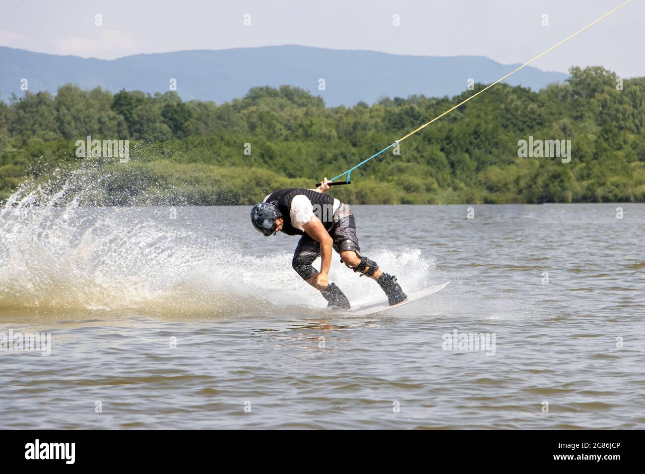 Ein Mann fährt auf dem Surfbrett. Ein Surfer wird auf einem Wasserschlepp auf dem See gezogen. Stockfoto