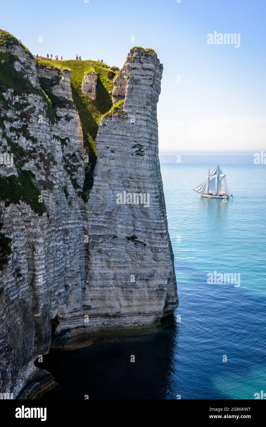 Ein weißes Segelschiff fährt an einem sonnigen Tag in voller See vor der Aval-Klippe in Etretat, Normandie. Stockfoto