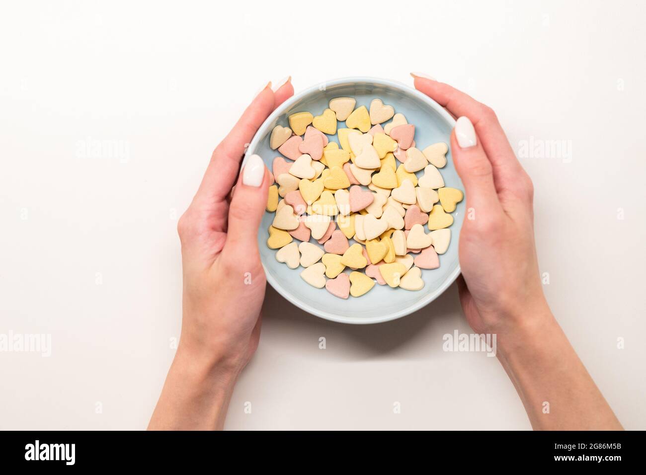 Frau Hände halten Schüssel mit Frühstücksflocken auf weißem Hintergrund. Gesunde Ernährung, gesunde Ernährung und Lebensstil Stockfoto