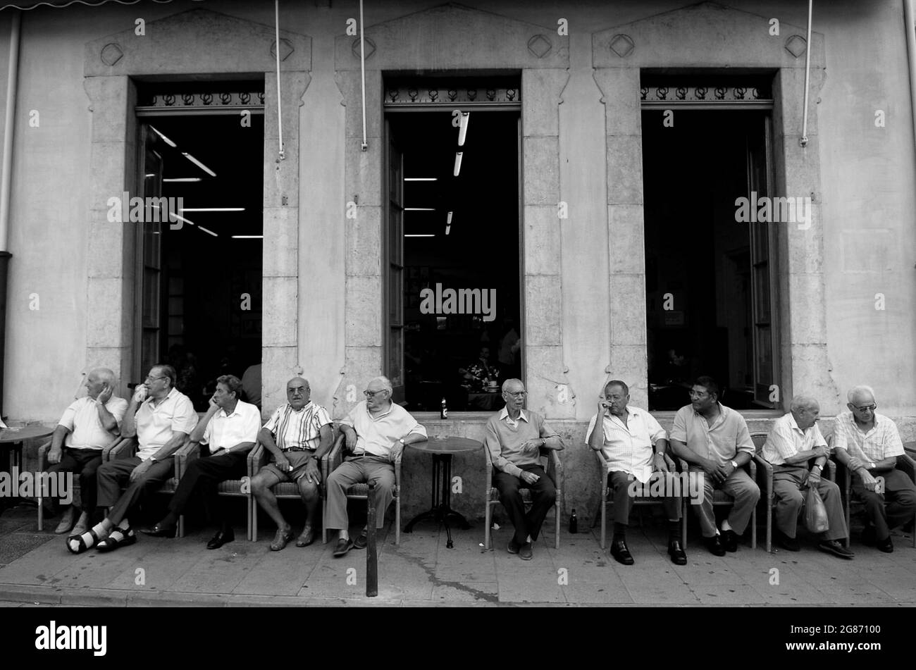 Beobachten der Welt, wie sie vorbei geht Lokale Männer unterhalten sich vor dem Brüderlichen Zentrum in Palafrugell, Katalonien, Spanien Stockfoto