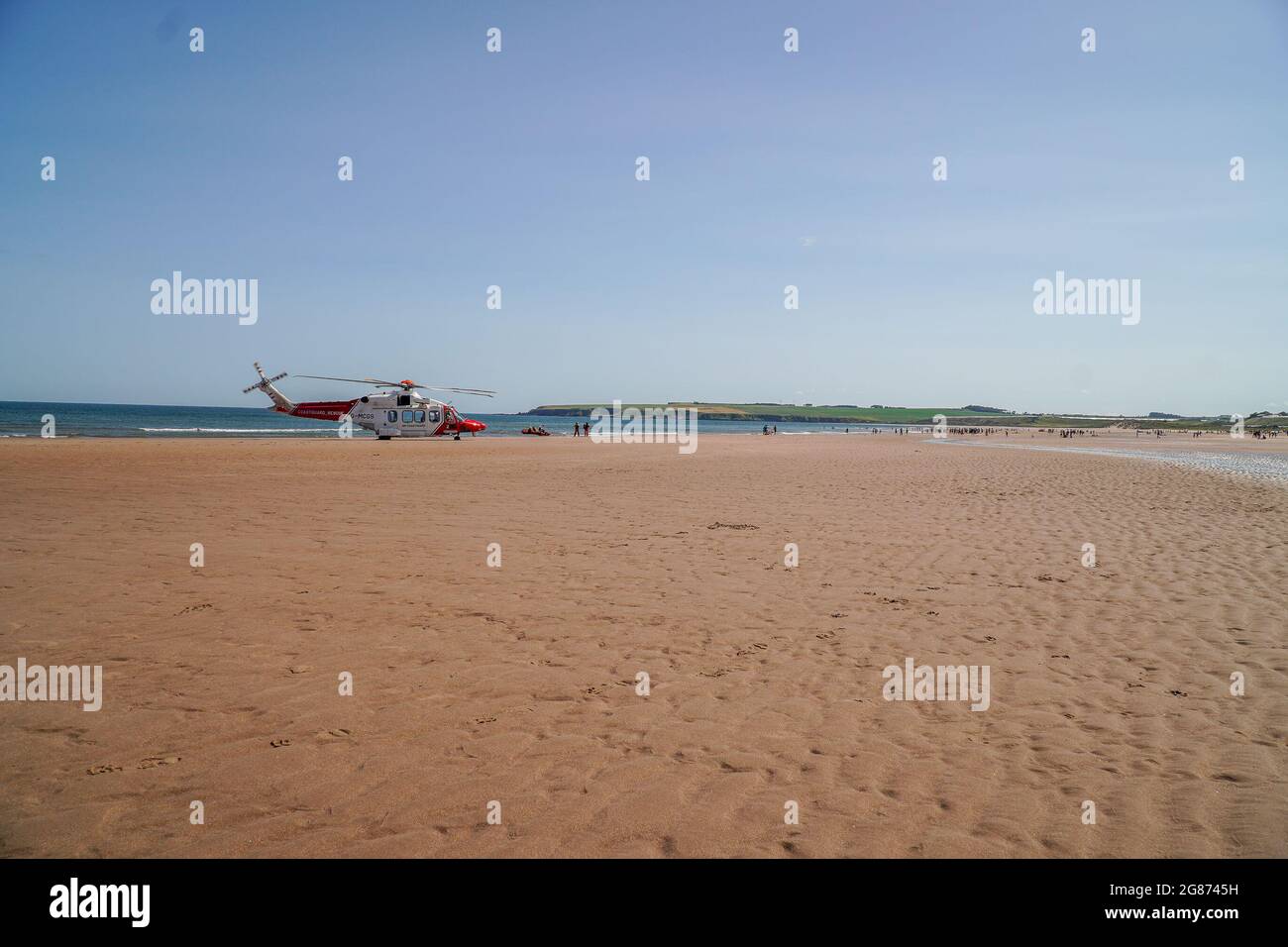 Lunan Bay Beach, Angus, Schottland, Großbritannien, 17. Juli 2021: Große Rettungsaktion der Küstenwache und RNLI, nachdem eine Mutter und Tochter heute am Lunan Bay Beach mit ihrem aufblasbaren Schlauchboot bei starkem Wind auf See getrieben wurden. Ein Offshore-Versorgungsschiff, das sich in der Nähe befand, startete ebenfalls den FRC, um bei der Rettung zu helfen. Auf diesem Foto können Sie den Küstenwache-Hubschrauber G-MCGS sehen, nachdem er am Strand gelandet war, große Menschenmengen im Hintergrund, nachdem Hunderte von Jahren den Lunan Bay Beach besucht hatten, um die hohen Sommertemperaturen zu genießen. (Quelle: Barry Nixon/Alamy Live News) Stockfoto