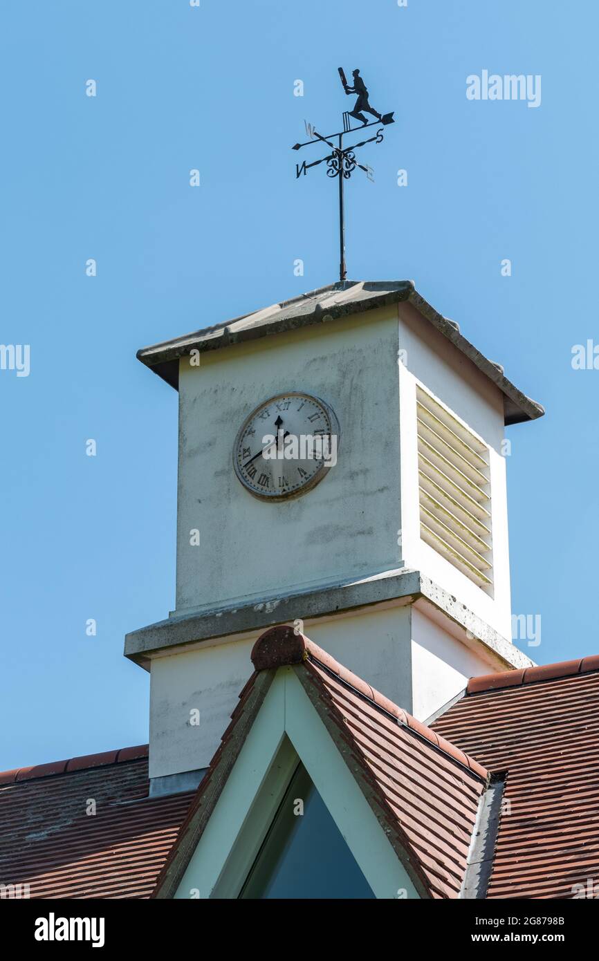 Uhrenturm und Kricketspieler-Wetterfahne auf dem Sport- oder Cricket-Pavillon im Hampshire-Dorf Robley, England, Großbritannien Stockfoto