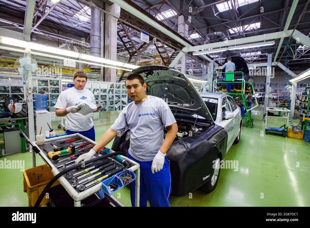 USt'-Kamenogorsk, Kasachstan, Mai 31,2012: Auto-Gebäude der Firma Asia-Auto. Arbeiter und Auto auf Montageband.Werkzeugwagen (links). Stockfoto