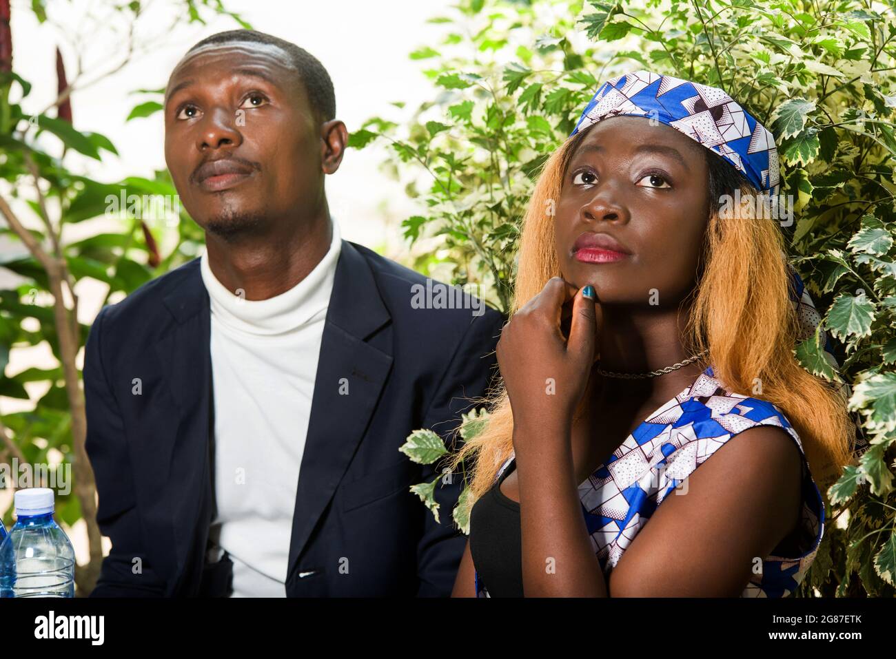 Schönes glückliches Paar, das am Tisch sitzt, redet und denkt, während es während eines romantischen Abendessens im Restaurant draußen wegschaut Stockfoto