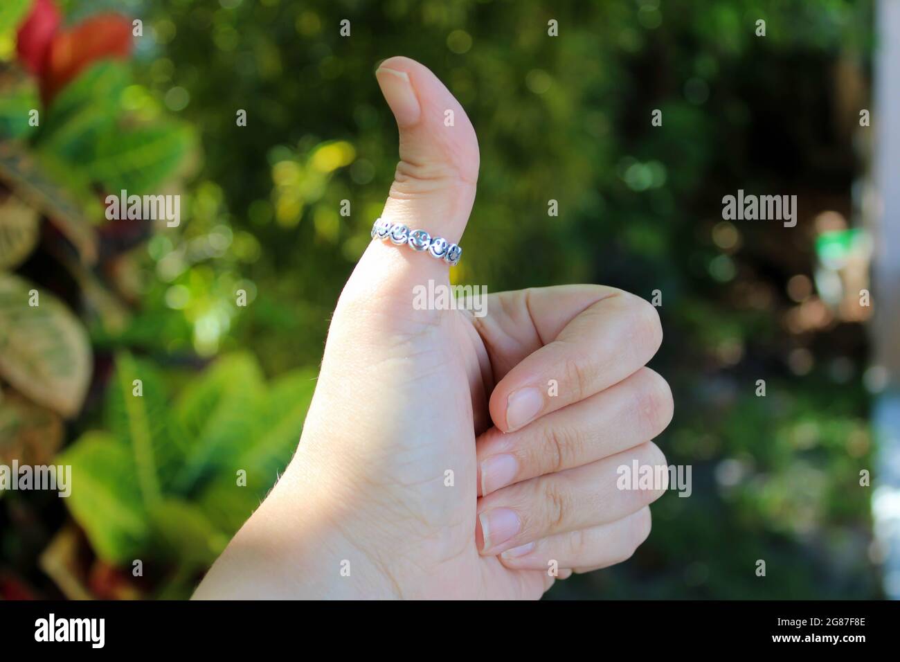 Die Hand einer Frau, die einen Daumen nach oben gibt, mit einem Ring am Daumen. Stockfoto