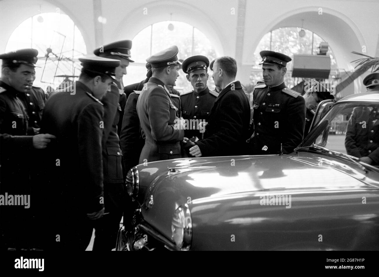 Russische und ostdeutsche Soldaten untersuchen neue Autos in Moskau 1956. Stockfoto