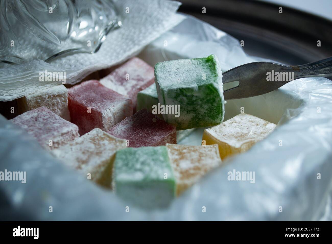 Türkische Delight farbenfroh in verpackter Box, Nahaufnahme von oben. Traditionelle Süßigkeiten mit kleiner Gabel. Stockfoto