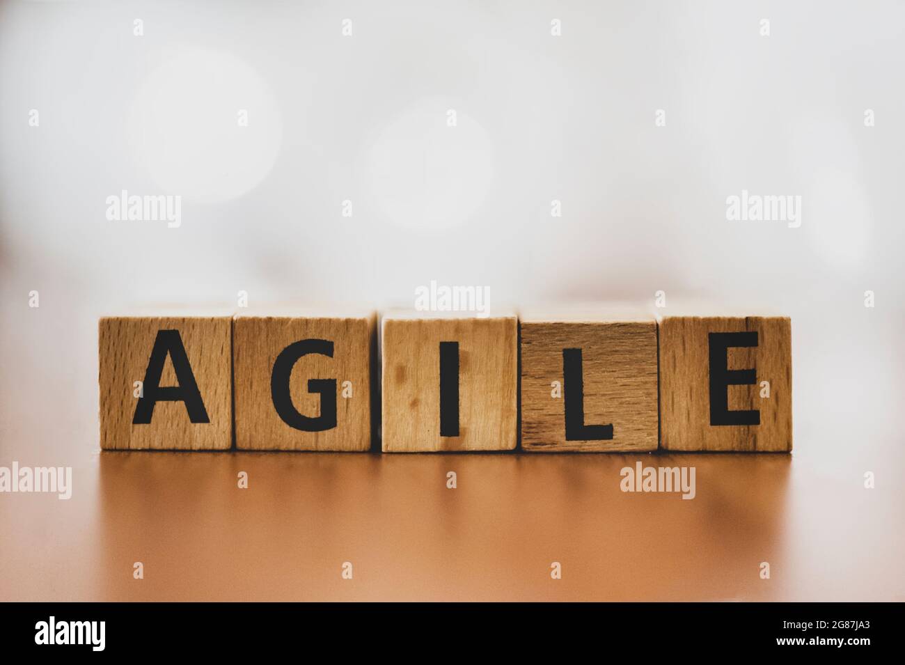 Der Orden „Agile“ wurde mit Holzblöcken vor einem sanft verschwommenen Hintergrund geschrieben. Dieses Bild zeigt das Wesen von Flexibilität und Innovation Stockfoto