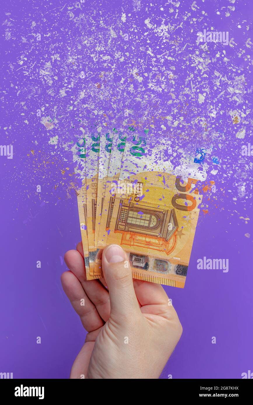 Geld ausgeben, alles Geld ausgeben ist Analphabet. Die Euro-Banknote verwandelt sich in Asche, löst sich vor purpurem Hintergrund auf. Vertikales Foto Stockfoto