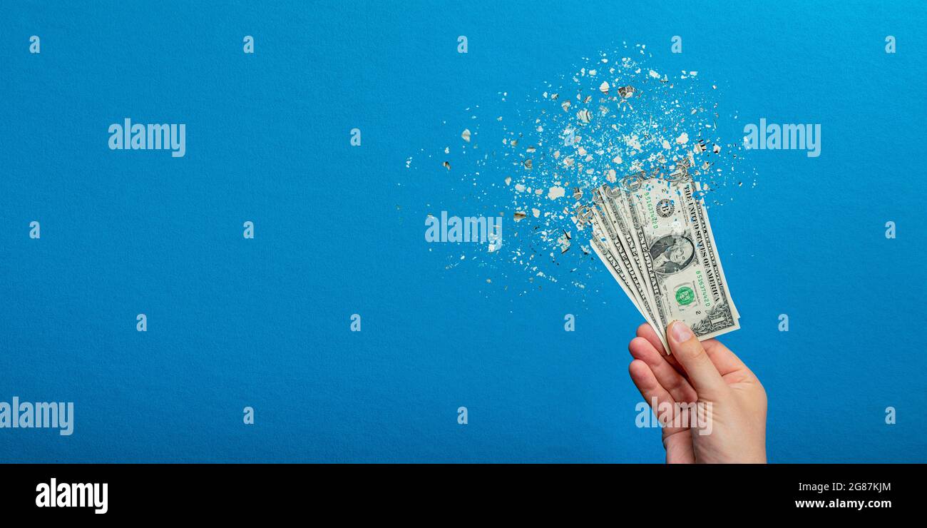 Inflation, Hyperinflation des Dollars. Banner mit blauem Hintergrund. Ein Dollarschein wird in die Hand eines Mannes auf blauem Hintergrund gesprüht. Preiserhöhung Stockfoto