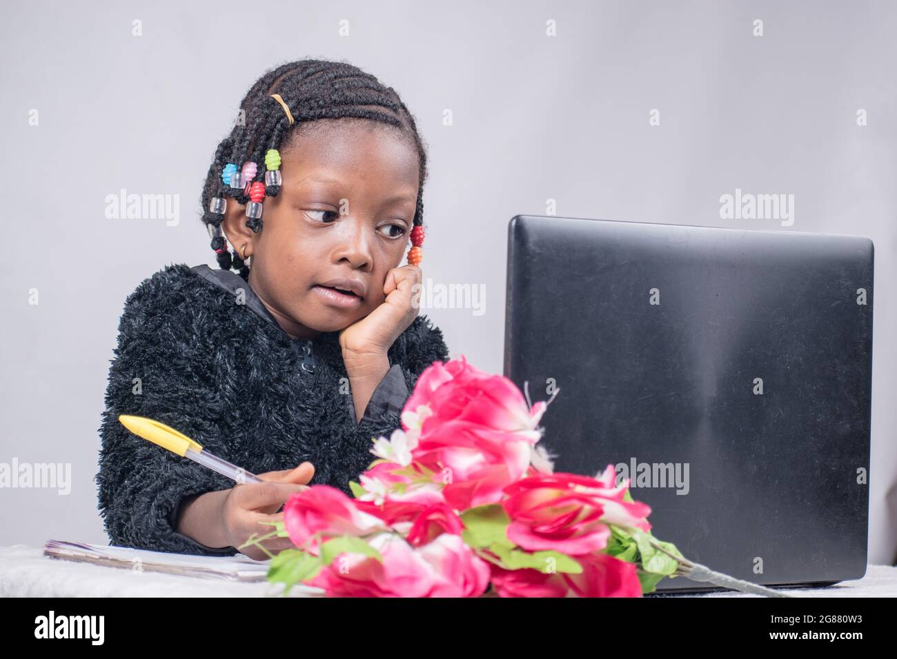 Afrikanisches Mädchen, Kind, das mit einem Laptop schreibt, studiert, lernt und forscht, um in ihrer Ausbildung hervorragende Ergebnisse zu erzielen Stockfoto
