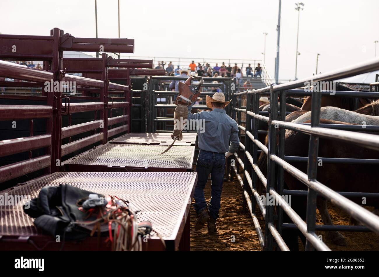 Bloomington, Usa. Juli 2021. Ein bareback Reiter holt sich seine Sattelausrüstung vor dem 3 Bar J Rodeo auf der Monroe County Fair. Die Monroe County Fair in Bloomington, Indiana, ist eine einwöchige Ausstellung für Kunsthandwerk, landwirtschaftliche Produkte und Viehzucht, ein Gemeindetreffen und ein Festival, das auf dem County Fairgrounds stattfindet. County Messen in den USA sind eine Tradition und Teil der Kultur tief in ländlichen amerikanischen Leben verwurzelt. County Messen begann vor langer Zeit als eine Möglichkeit für Landwirte und landwirtschaftliche Arbeitnehmer zu sammeln und Kontakte zu knüpfen. Kredit: SOPA Images Limited/Alamy Live Nachrichten Stockfoto