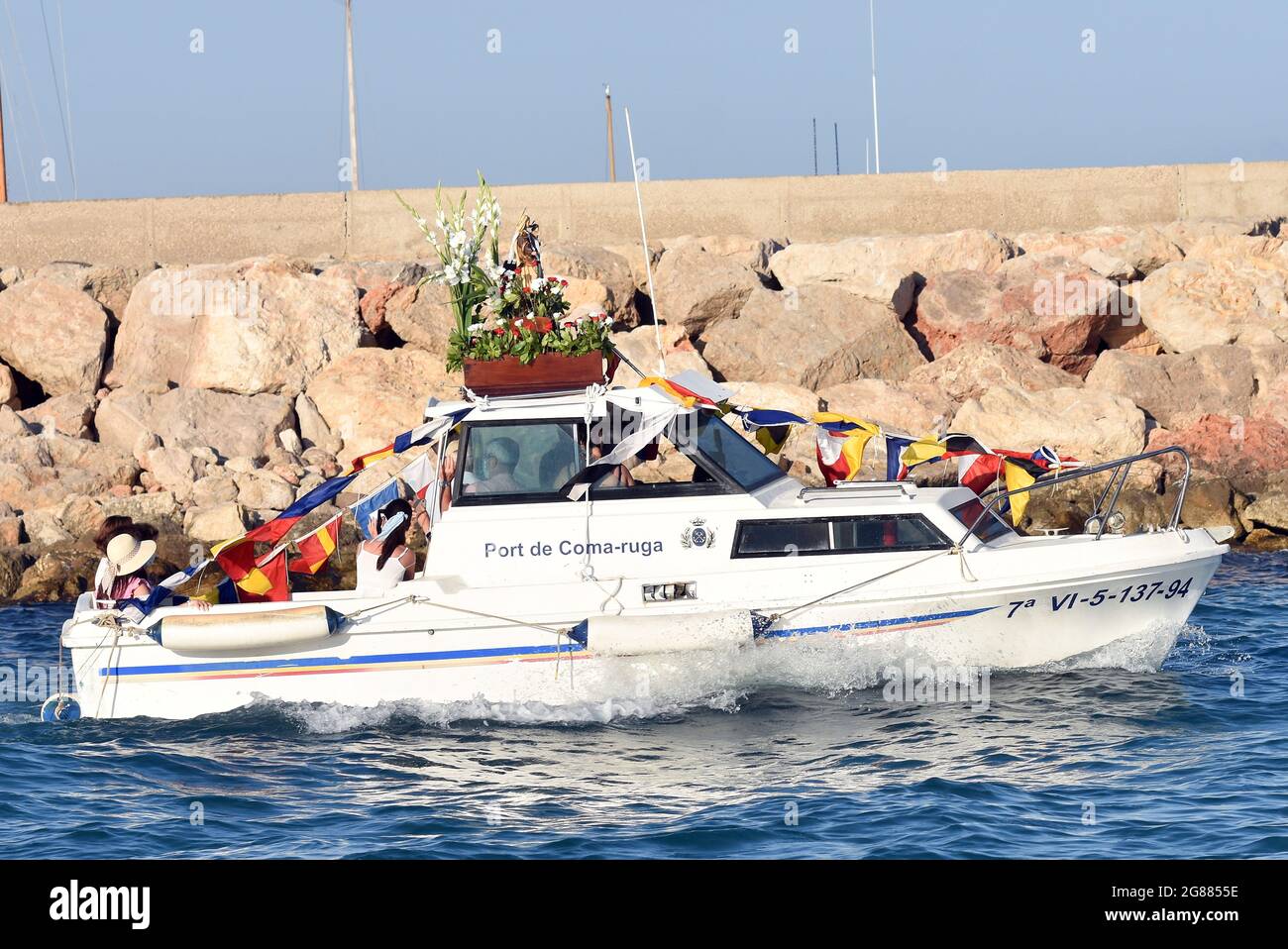 Ein Blick auf ein Boot, das mit einer Statue der Virgen del Carmen während der Seefahrt Prozession in Vendrell führt. Jedes Jahr am 16. Juli wird ein religiöses Fest zu Ehren der Virgen del Carmen, der schutzpatronin der Seefahrer und Fischer, gefeiert, obwohl die Feier am 16. Juli stattfindet, die Prozession am Wochenende stattfindet, damit mehr Menschen an der Feier teilnehmen können. Die Statue der Jungfrau, wird von einer Gruppe von Menschen, die es zu einem Boot verlassen während der Prozession durch das Wasser des Meeres in der Nähe des Hafens, gefolgt von mehreren Booten getragen. Stockfoto