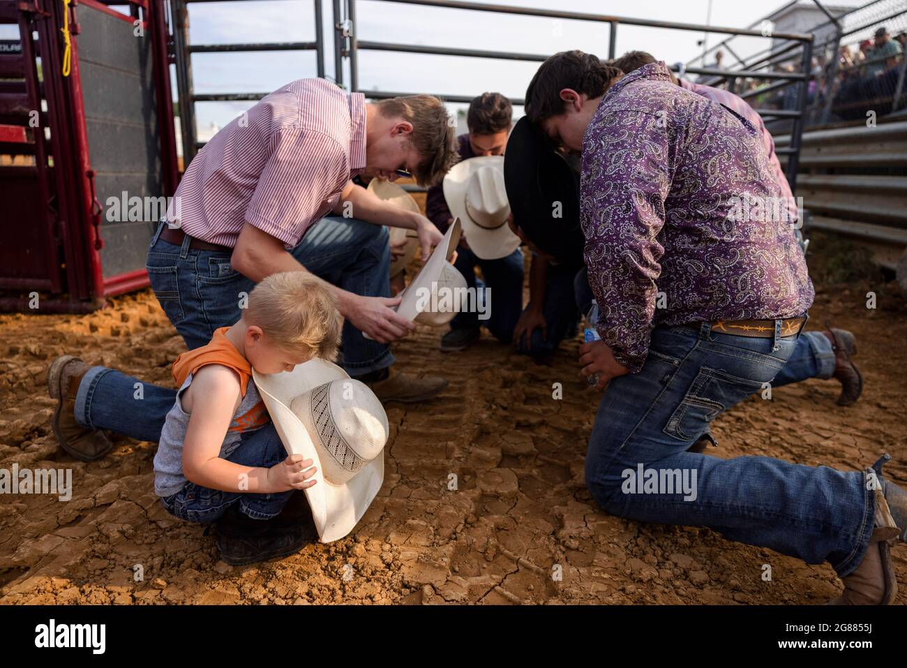 Bloomington, Usa. Juli 2021. Ein Junge betet mit einer Gruppe von Rodeo-Teilnehmern vor dem 3 Bar J Rodeo auf der Monroe County Fair. Die Monroe County Fair in Bloomington, Indiana, ist eine einwöchige Ausstellung für Kunsthandwerk, landwirtschaftliche Produkte und Viehzucht, ein Gemeindetreffen und ein Festival, das auf dem County Fairgrounds stattfindet. County Messen in den USA sind eine Tradition und Teil der Kultur tief in ländlichen amerikanischen Leben verwurzelt. County Messen begann vor langer Zeit als eine Möglichkeit für Landwirte und landwirtschaftliche Arbeitnehmer zu sammeln und Kontakte zu knüpfen. Kredit: SOPA Images Limited/Alamy Live Nachrichten Stockfoto