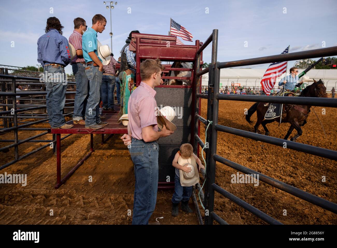 Ein Junge hört mit einer Gruppe von Rodeo-Teilnehmern vor dem 3 Bar J Rodeo auf der Monroe County Fair das Spielen der Nationalhymne. Die Monroe County Fair in Bloomington, Indiana, ist eine einwöchige Ausstellung für Kunsthandwerk, landwirtschaftliche Produkte und Viehzucht, ein Gemeindetreffen und ein Festival, das auf dem County Fairgrounds stattfindet. County Messen in den USA sind eine Tradition und Teil der Kultur tief in ländlichen amerikanischen Leben verwurzelt. County Messen begann vor langer Zeit als eine Möglichkeit für Landwirte und landwirtschaftliche Arbeitnehmer zu sammeln und Kontakte zu knüpfen. Stockfoto