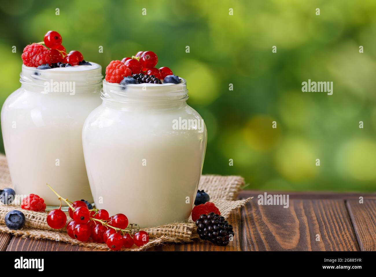 Joghurt und frische Beeren in zwei Gläsern auf dem Tisch im Freien Stockfoto