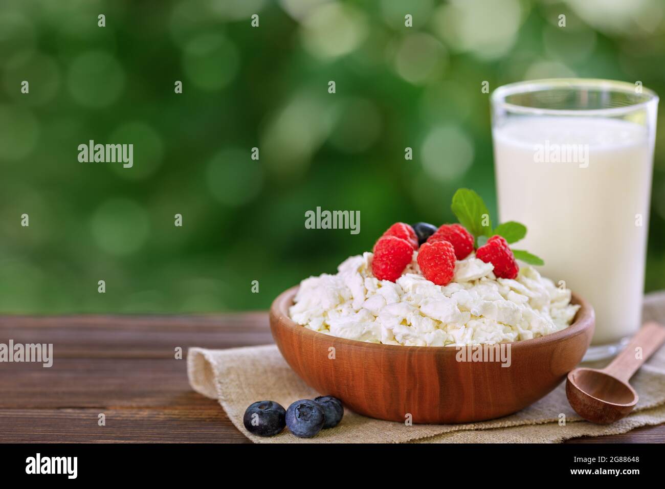 Joghurt im Glas und Hüttenkäse mit frischen Beeren auf dem Tisch im Freien Stockfoto