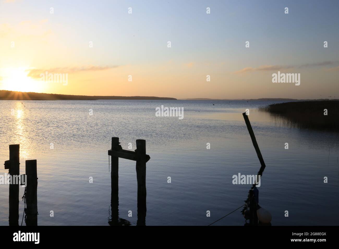 Sonnenuntergang an der Küste des Sees. Naturlandschaft. Reflexion, blauer Himmel und gelbes Sonnenlicht Stockfoto