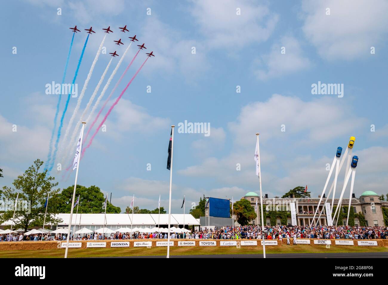 RAF Red Arrows fliegen beim Goodwood Festival of Speed 2013 über das Goodwood House, mit Zuschauern und Skulpturen von Porsche-Autos. Flipast Stockfoto