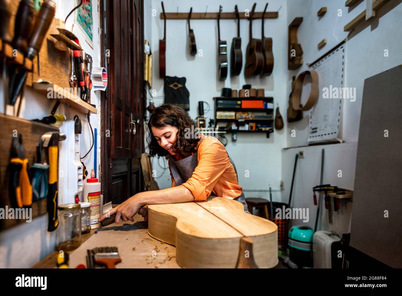 Eine Geigenbauerin, die in ihrer Musikinstrumentenwerkstatt Gitarren macht Stockfoto