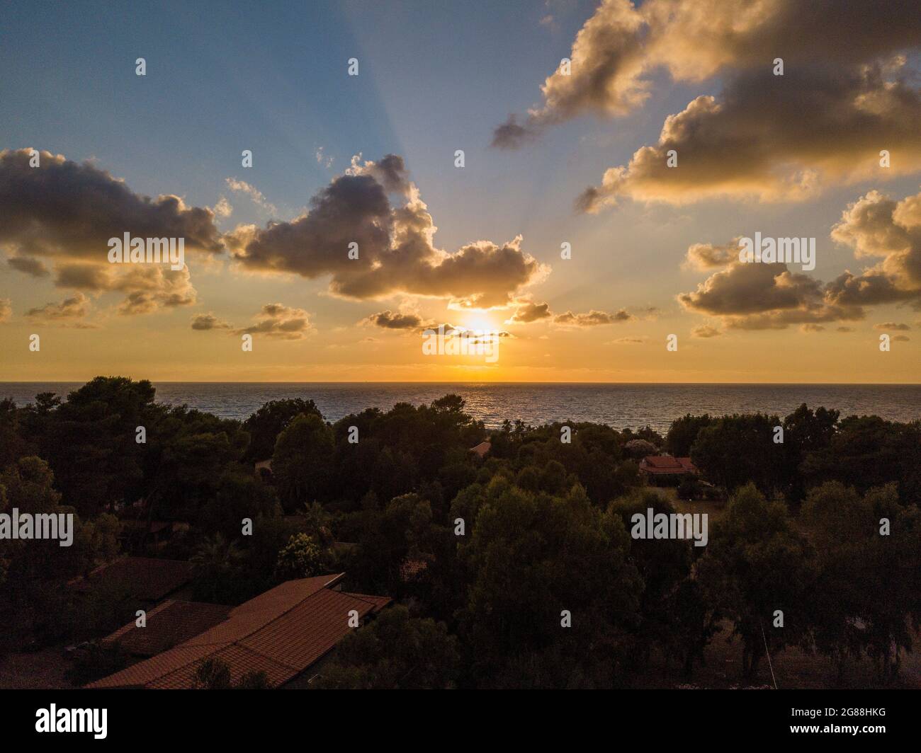 Luftaufnahme eines Sonnenuntergangs über dem Meer in Zambrone, Küste von Kalabrien. Italien. Häuser und Bäume in der Nähe des Strandes mit Sonnenschirmen. Ferienorte, Urlaub Stockfoto