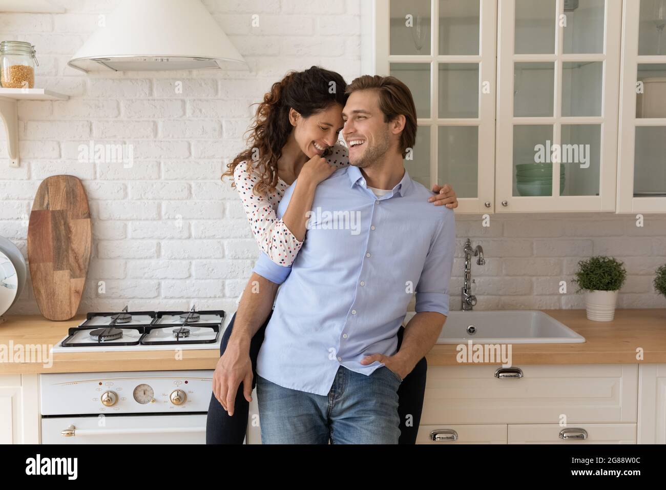 Liebende junge verheiratete Paar kuscheln in der Küche mit Spaß zusammen Stockfoto