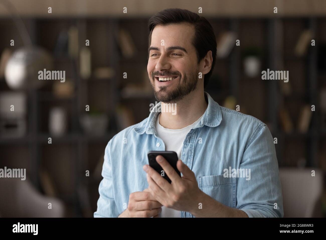 Glücklich verträumt junger Mann hält Smartphone in den Händen. Stockfoto