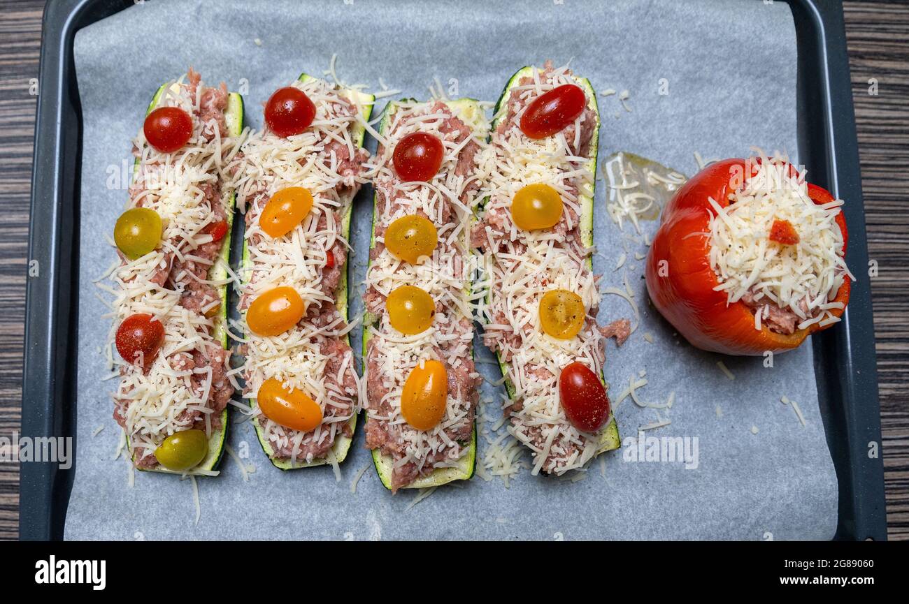 Ein Blick von oben auf ungekochte Auberginen und Pfeffer, gefüllt mit Tomaten und Käse auf einem Tablett Stockfoto