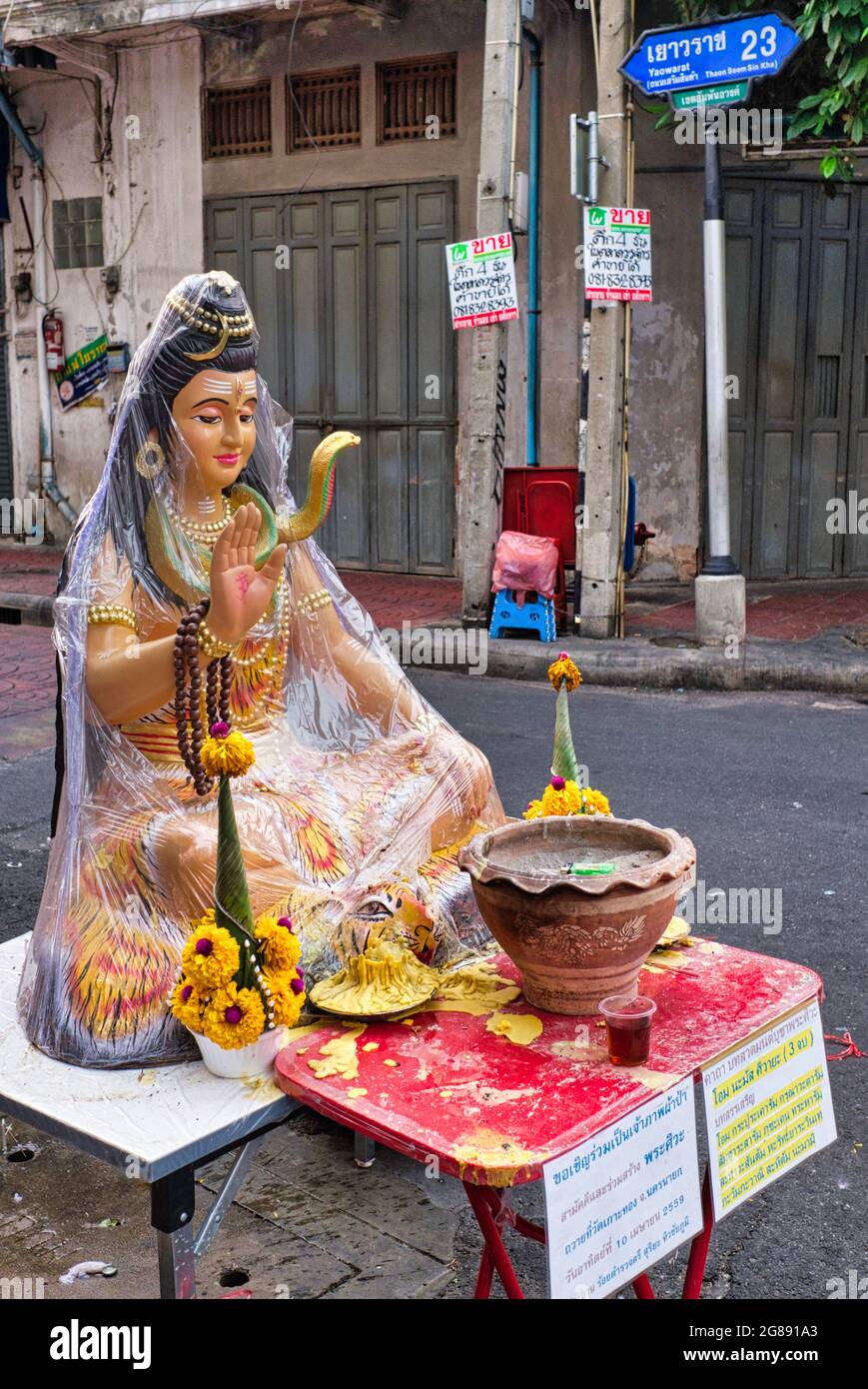 Ein Schrein mit einer Figur von Shiva, dem hinduistischen gott der Zerstörung und Wiedergeburt oder Neuschöpfung, der in einer Gasse in Chinatown, Bangkok, Thailand, aufgestellt wurde Stockfoto