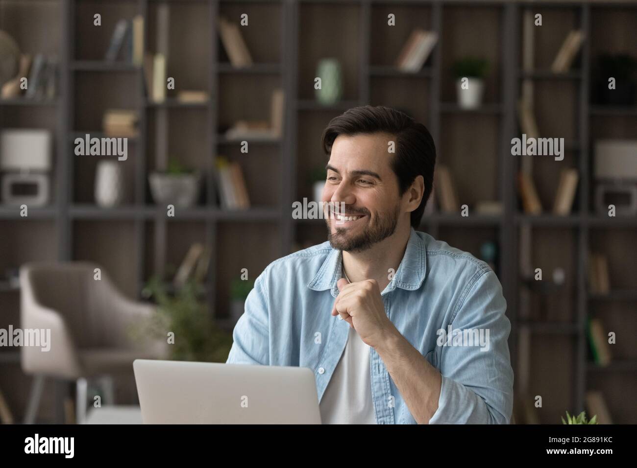 Glücklicher, verträumter Mann, der in die Ferne schaut, abgelenkt von der Computerarbeit. Stockfoto