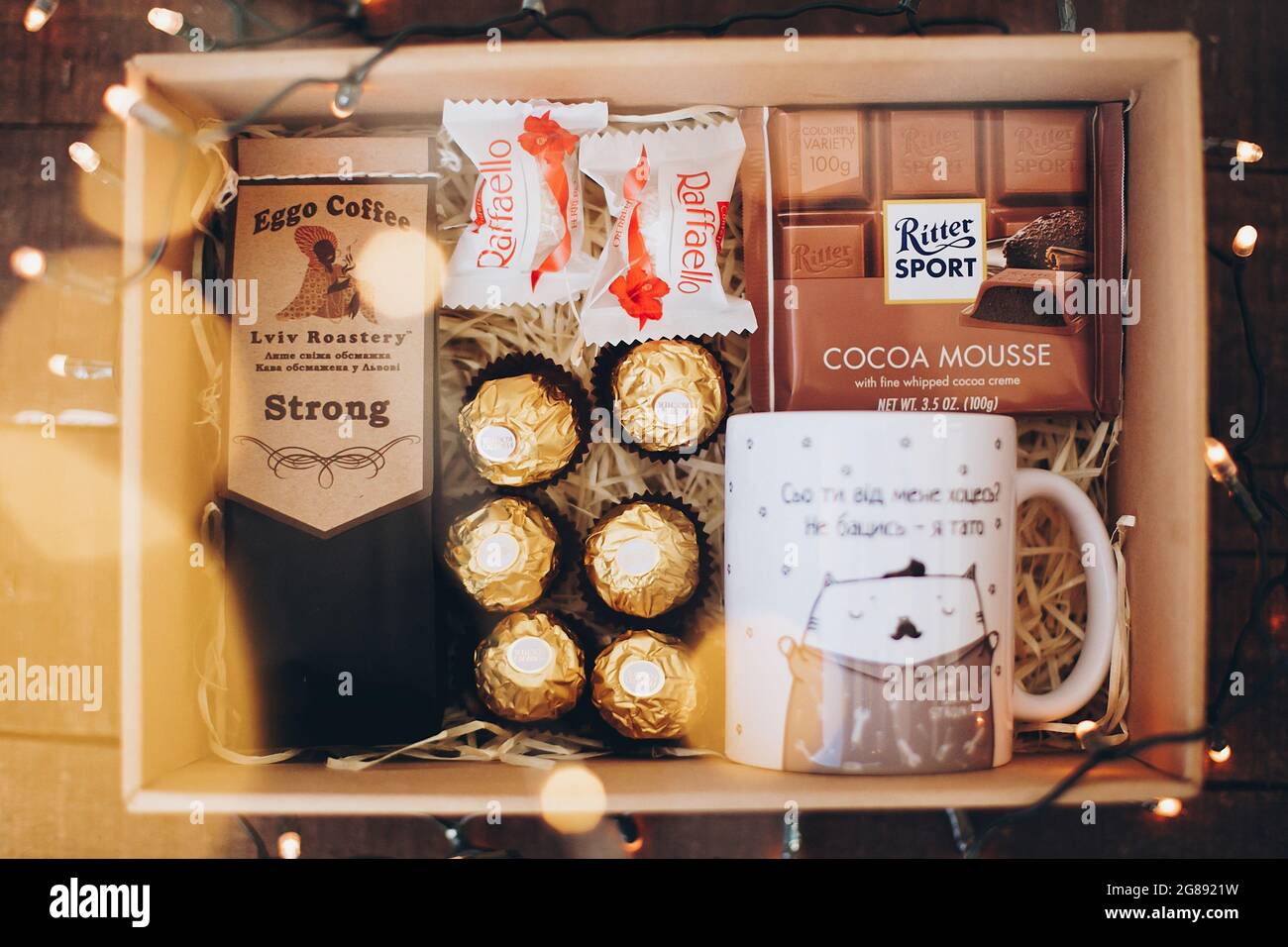 Lviv, Ukraine - 1. Dezember 2017: Gerösteter Kaffee, Tasse, ritter Sport  Schokolade und rafaello auf Stroh in Lichter in Geschenkbox. Stilvolle  Kaffee-Geschenkbox für Stockfotografie - Alamy
