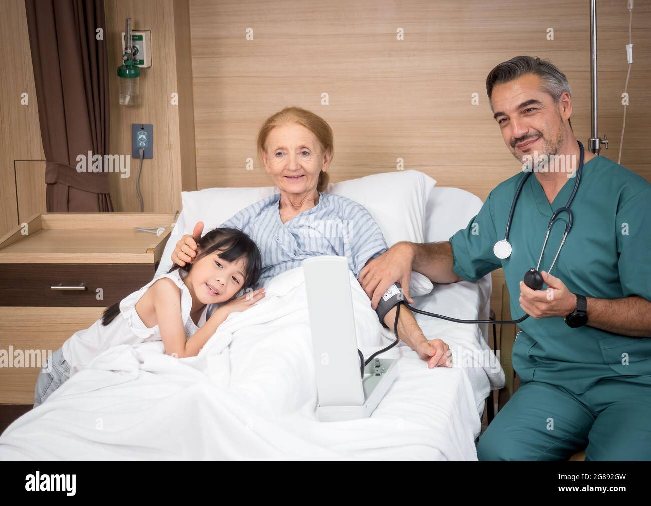 Arzt mit einem niedlichen kleinen Mädchen und einer älteren Patientin, die im Krankenhaus Anzeichen für OK zeigt. Medizin und Gesundheitskonzept. Stockfoto