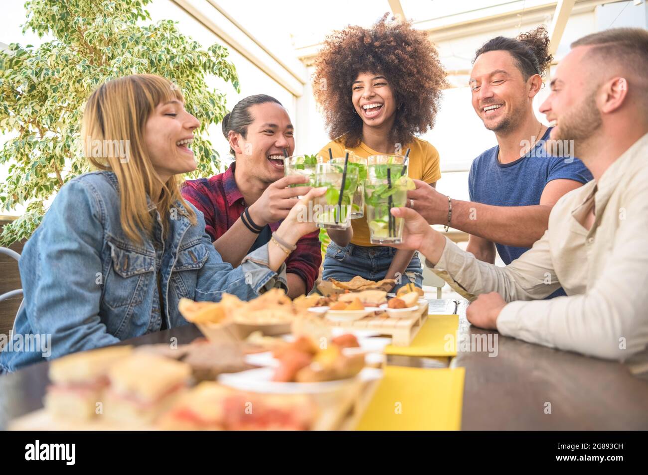 Fröhliche Gruppe von multirassischen Freunden, die Mojito-Cocktails trinken und im Restaurant der Brauerei-Bar toasten - Freundschaftskonzept mit jungen Leuten, die drun trinken Stockfoto
