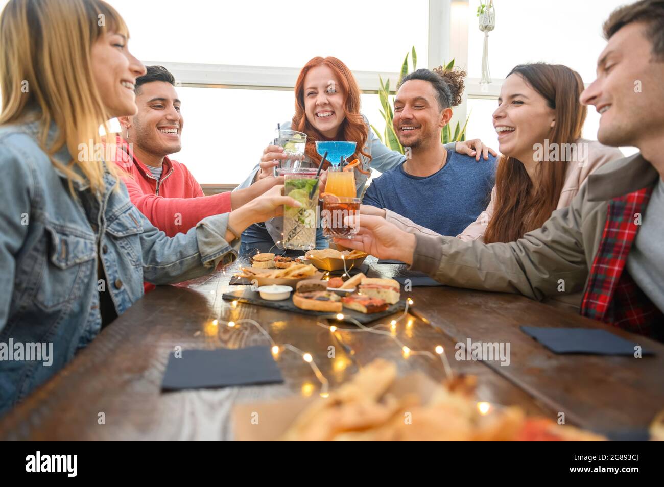 Multirassische Freunde trinken farbigen Cocktail an der Bar des Restaurants - Freundschaftskonzept mit jungen Menschen, die Spaß haben, zusammen Getränke auf ha zu toasten Stockfoto