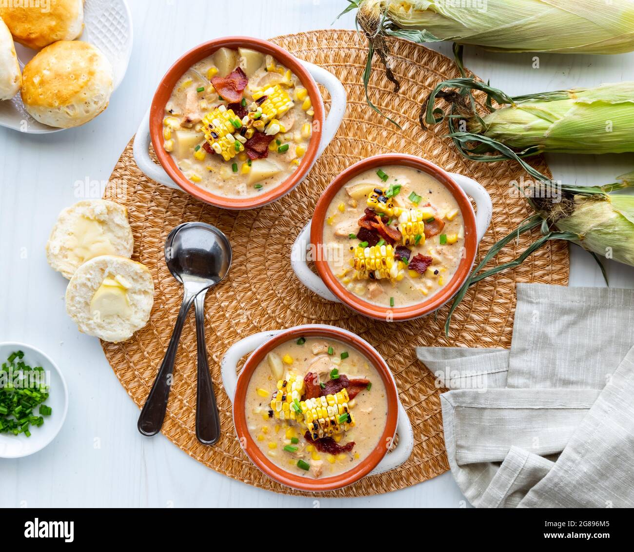 Draufsicht auf Hühnchen und Maiskolben in Suppenbrötchen mit gegrilltem Mais und Speck, fertig zum Essen. Stockfoto