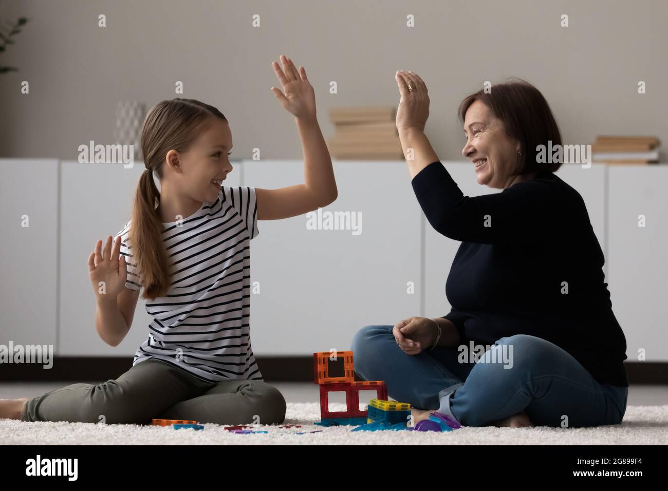 Glücklich Mädchen und Oma spielen auf Heizung Boden, Stockfoto