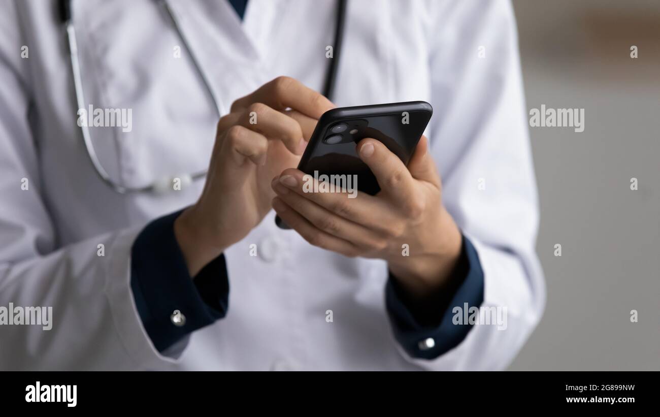 Hände des Arztes in weißem Mantel mit Mobiltelefon Stockfoto