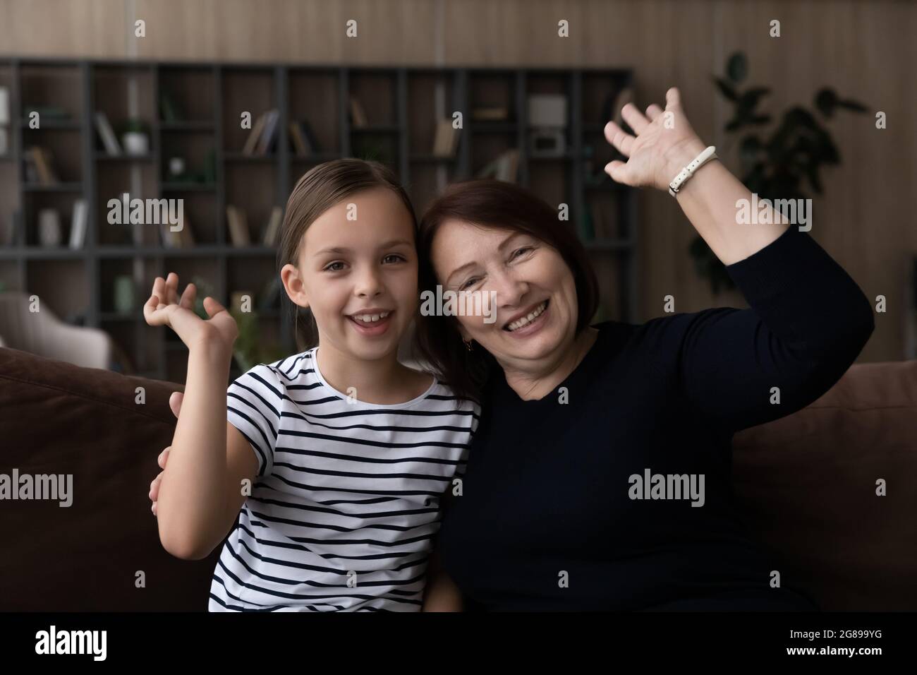 Glückliches Mädchen und Großmutter winken Hallo an die Kamera Stockfoto