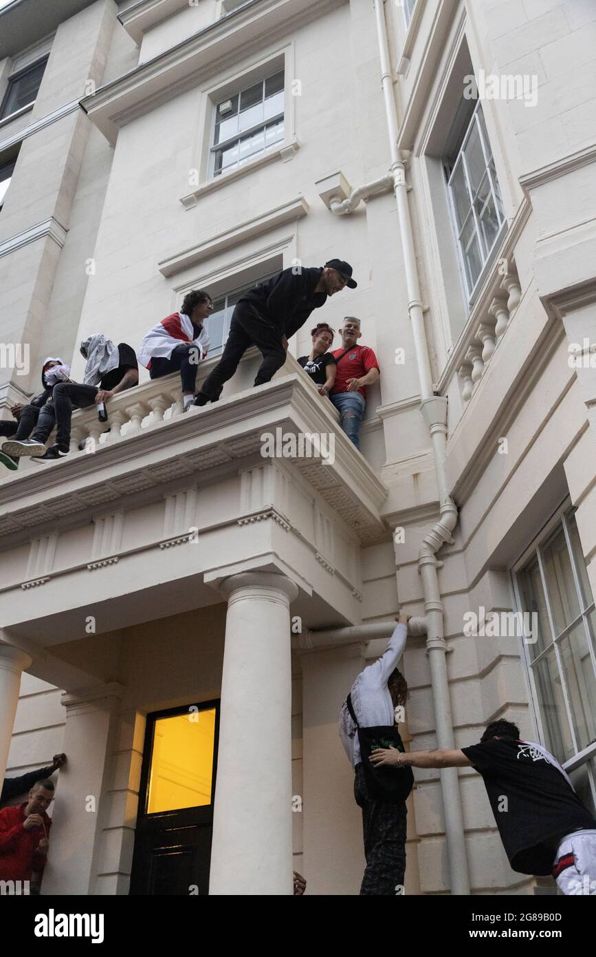 England-Fans klettern während des Finales der EM 2020 zwischen England und Italien, Trafalgar Square, London, 11. Juli 2021 Stockfoto