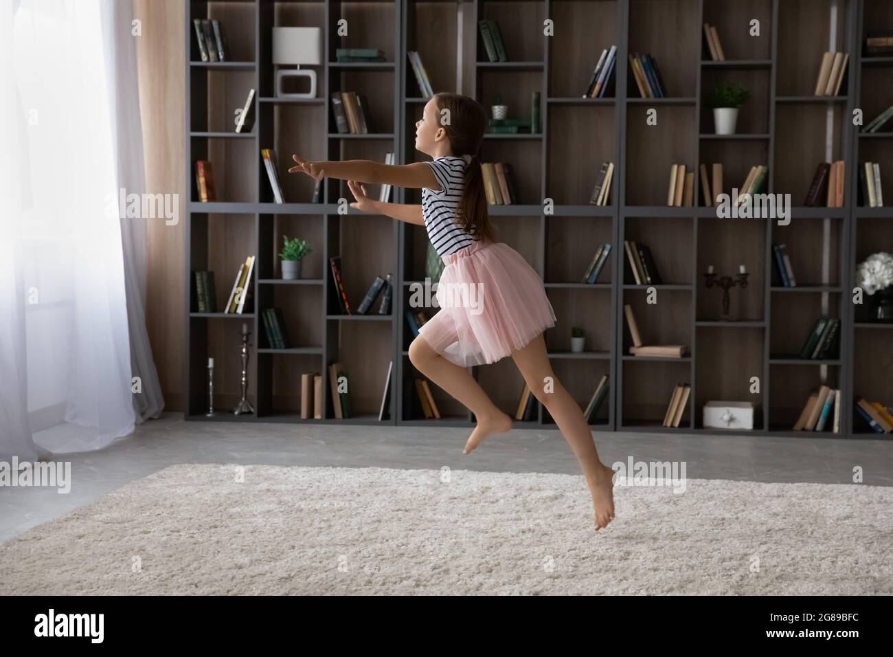 Aufgeregt Mädchen in rosa Rock tanzen zu Musik zu Hause Stockfoto