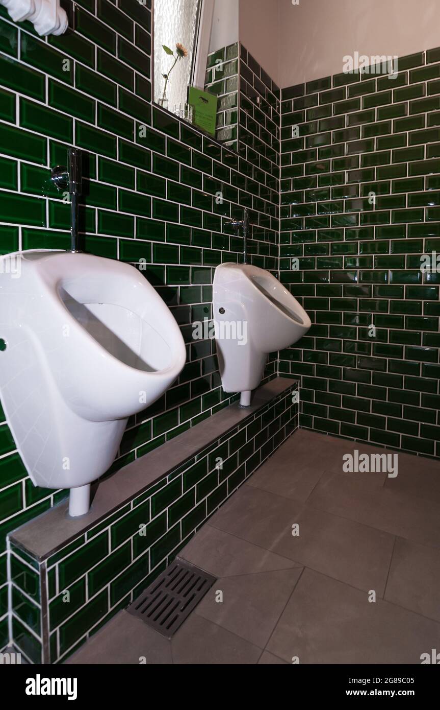 Blick in eine außergewöhnliche Gästetoilette. Mit zwei Urinalen. Besonders auffällig sind die kleinen grünen Fliesen Stockfoto