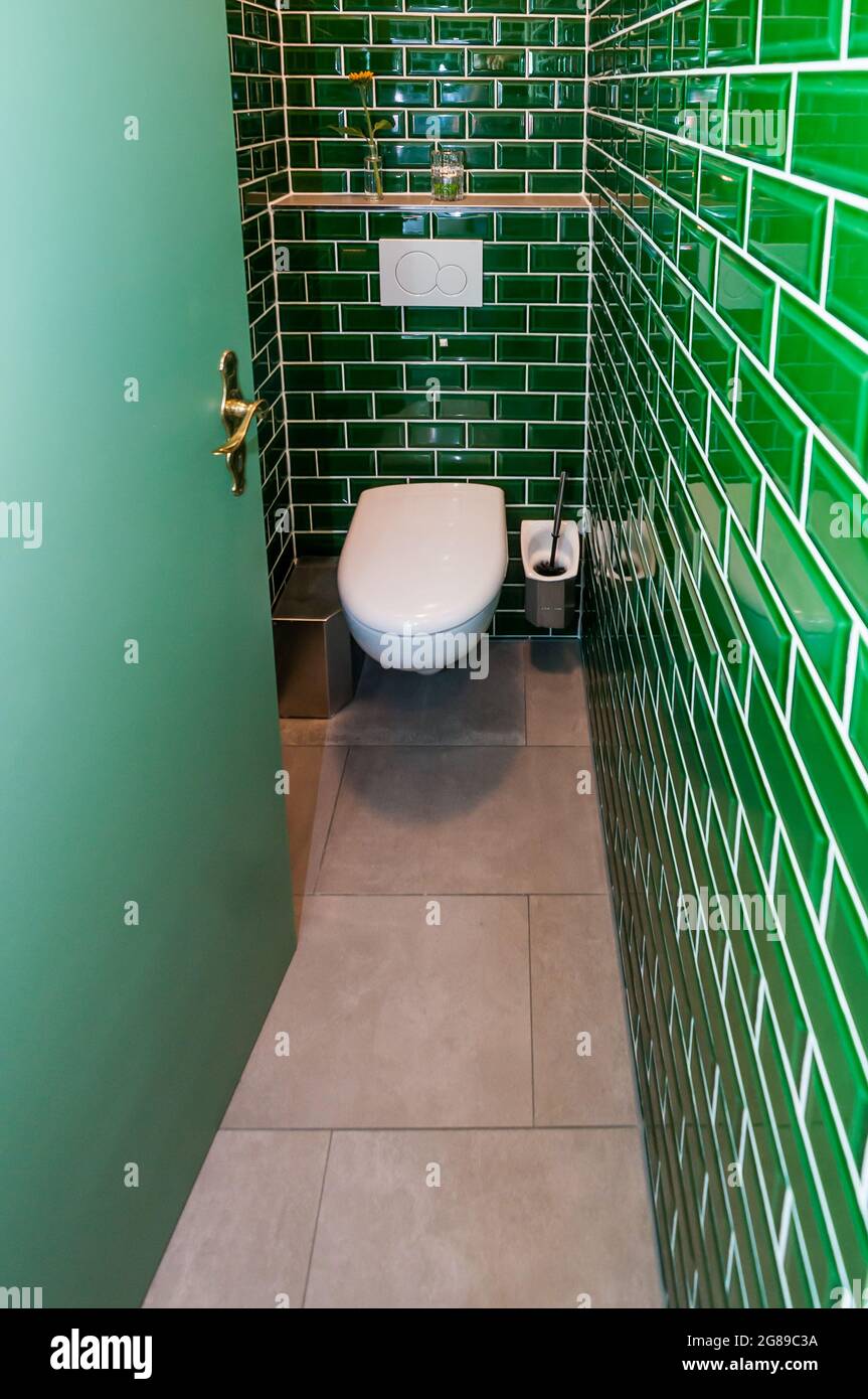 Blick in eine außergewöhnliche Gästetoilette. Besonders auffällig sind die kleinen grünen Fliesen Stockfoto