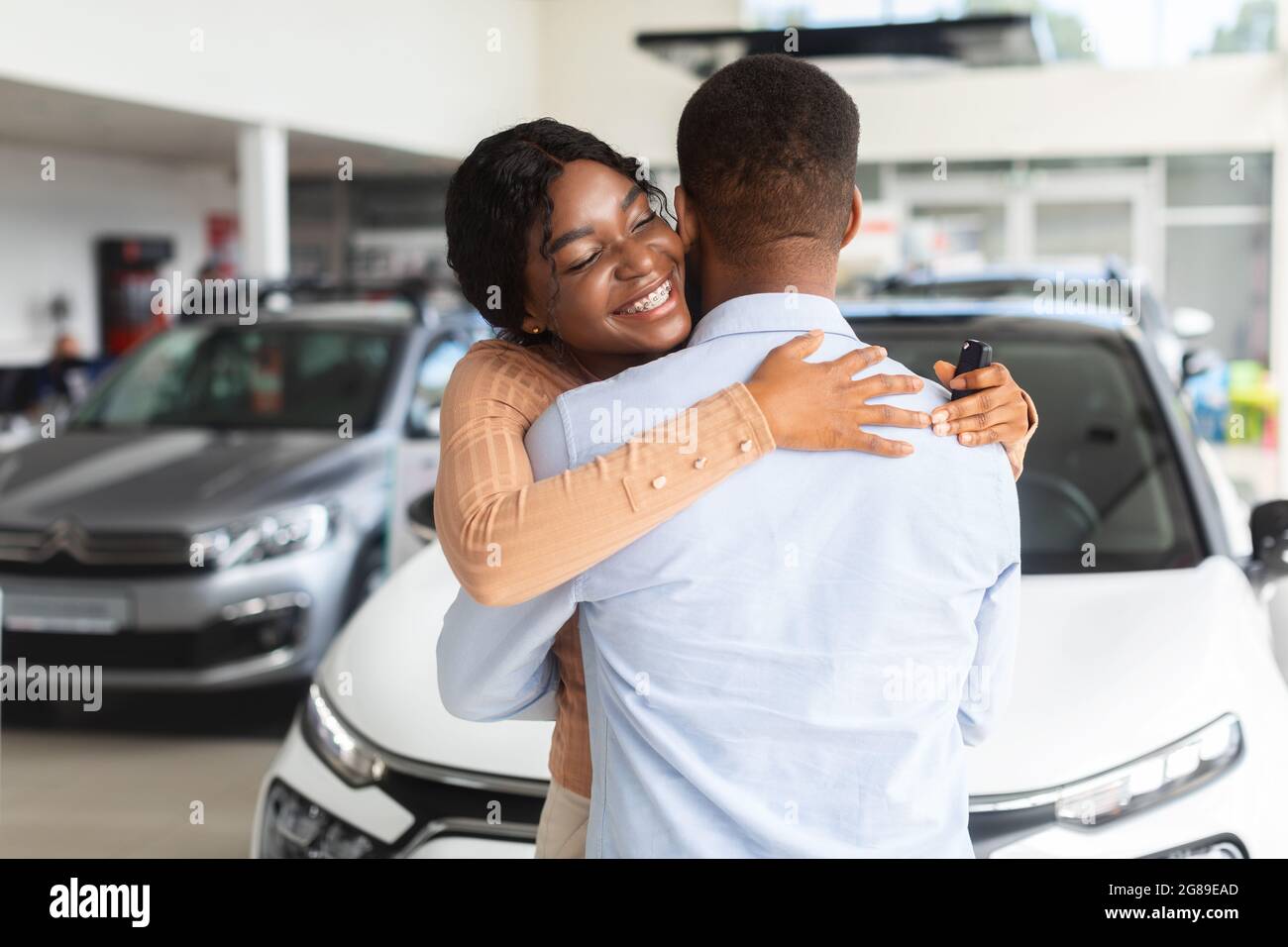 Grateful Black Ehefrau Umarmen Ehemann Nach Dem Kauf Von Neuwagen In Autohaus Showroom Stockfoto