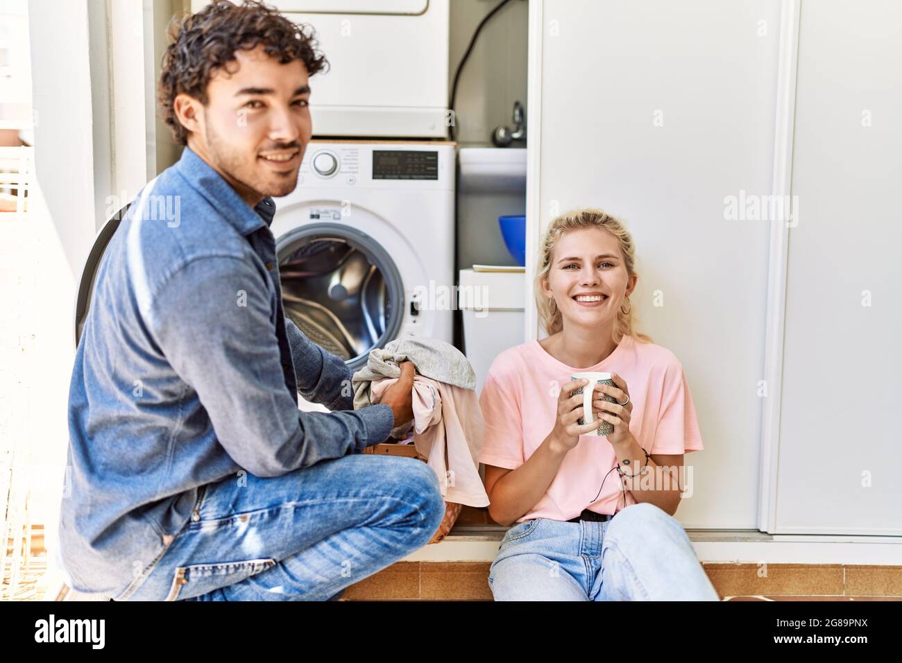 Junges Paar lächelt glücklich Kaffee trinken, während die Wäsche zu Hause. Stockfoto