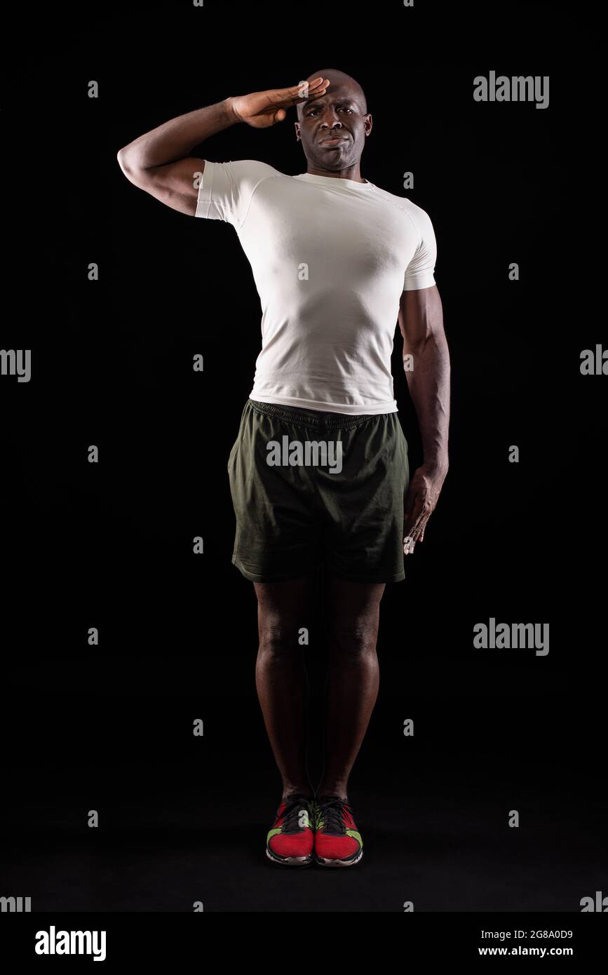afroamerikanischer Mann begrüßt die Kamera mit einem militärischen Gruß im Studio Stockfoto