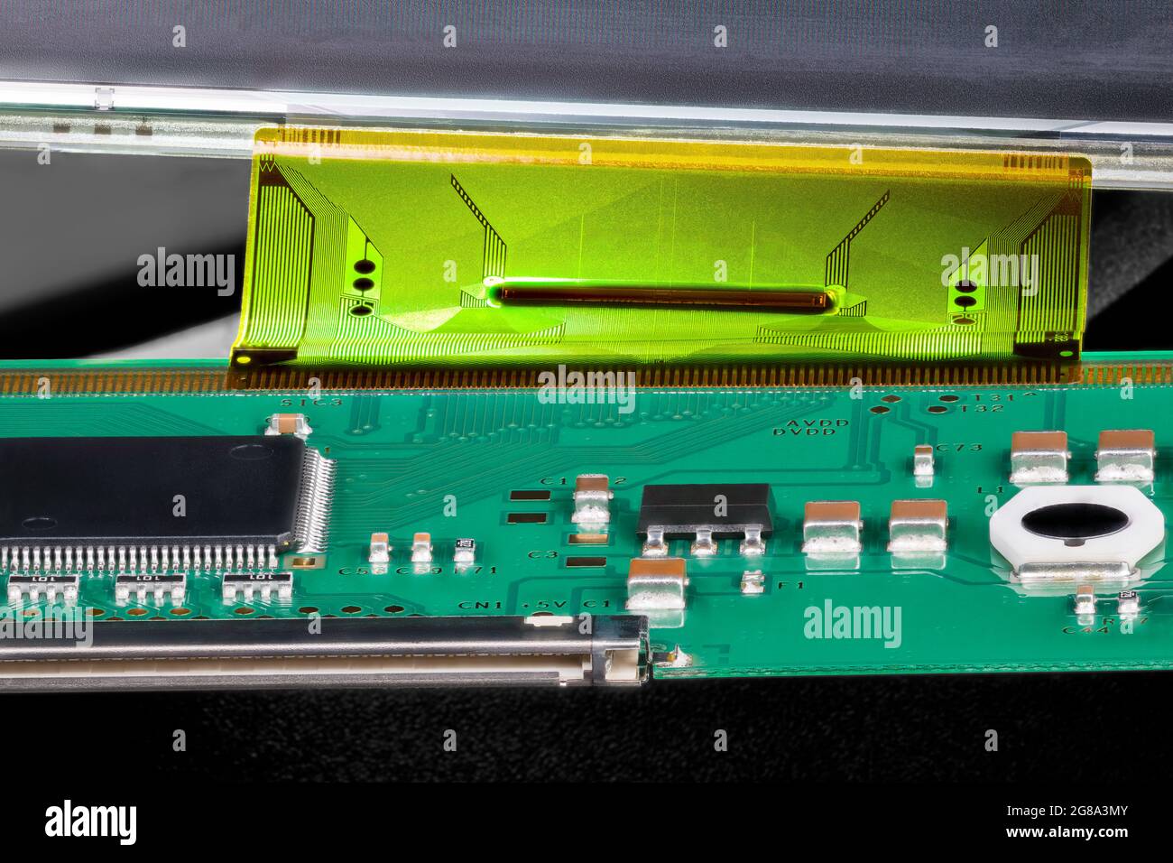 Leiterplatte, die über ein flexibles Flachbandkabel mit dem LCD-Panel verbunden ist. Nahaufnahme von elektronischen Komponenten - Mikrochip, Induktor oder Kondensator auf grüner Leiterplatte. Stockfoto