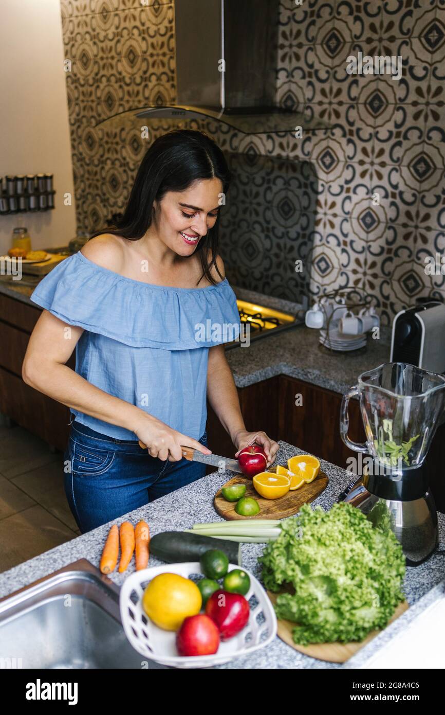 Lateinische Frau, die grünen Smoothie oder Detox-Saft in der Küche zu Hause in gesunden Ernährung Konzept in Mexiko Stockfoto